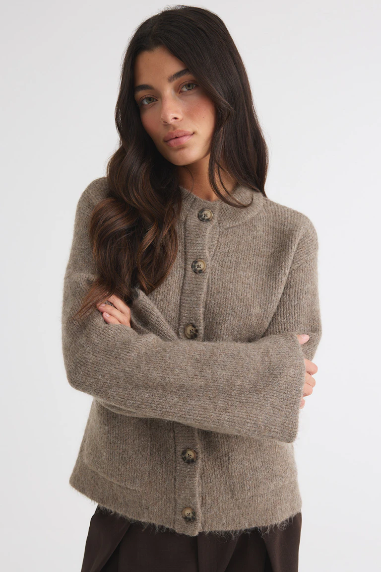 Taupe fuzzy button-front cardigan with long sleeves, paired with dark brown trousers.