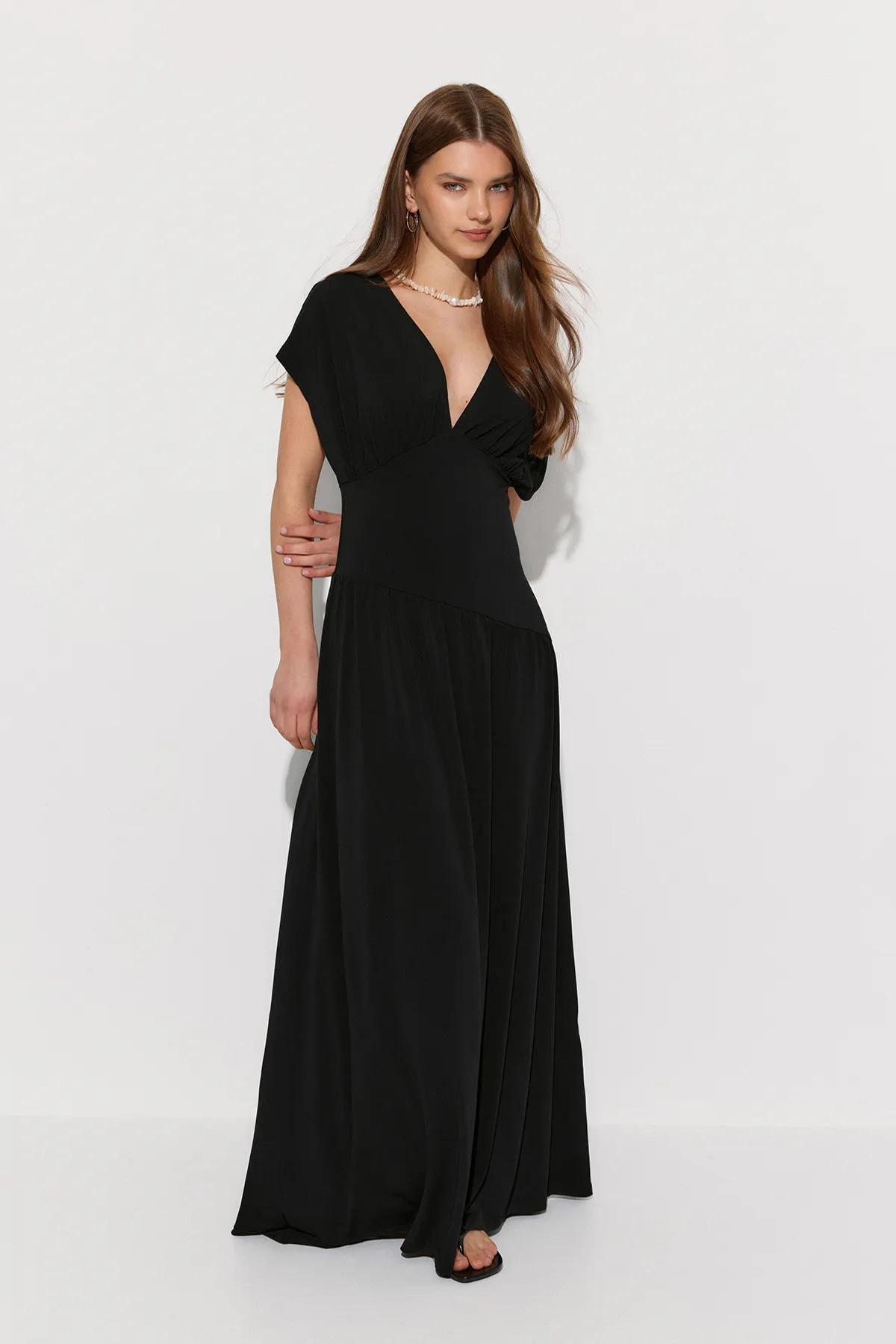 Black floor-length dress with a deep V-neckline, short cap sleeves, fitted waist and flowing skirt.