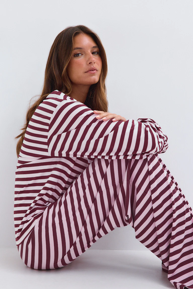 ID 331646 — StyleColorSupplier 12651: Tvådelat set i randigt mönster i vinrött och ljusrosa, bestående av en långärmad topp och matchande byxor med vida ben.