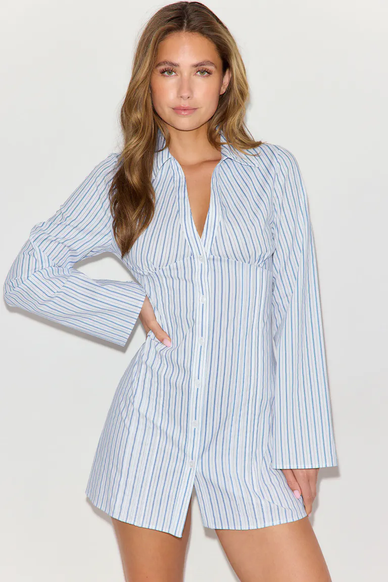 Robe-chemise à rayures verticales bleu clair et blanches, boutonnée sur le devant, avec col pointu, dessous de poitrine ajusté, manches longues évasées et ourlet court avec fente sur le devant.