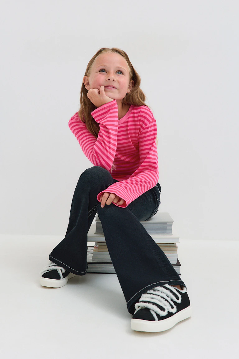 ID 332219 | StyleColorSupplier 16557: Rosa stripete langermet topp, svarte jeans med utvidet ben og svarte joggesko med hvite snørebånd og hvite såler.