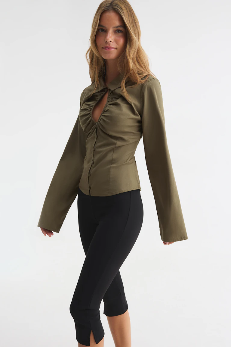 ID 332451, StyleColorSupplier 13018: Olivengrøn langærmet bluse med rynker og knapper foran samt sorte, korte leggings.