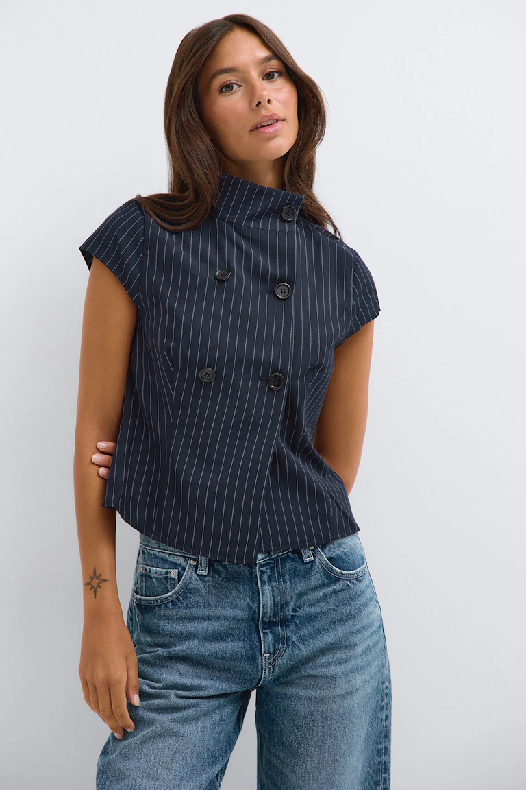 Référence 332719, StyleColorSupplier 16657 : haut sans manches à double boutonnage à fines rayures bleu marine, porté avec un jean bleu.