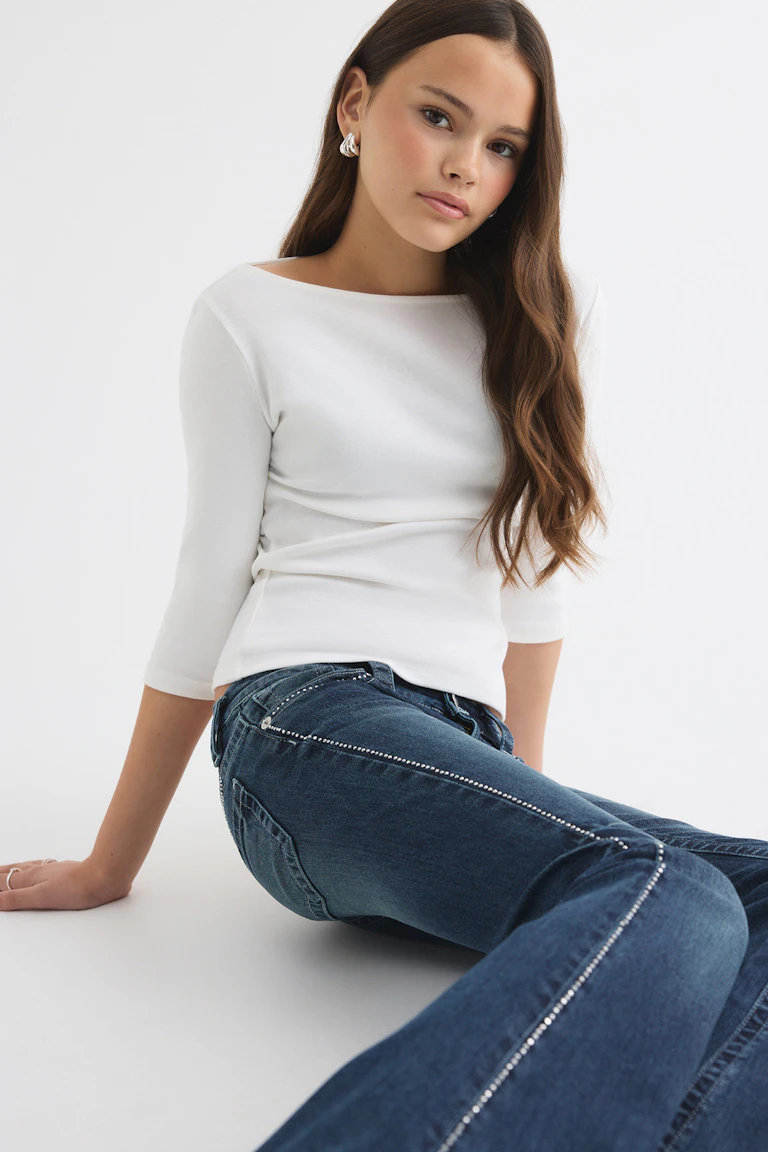 White fitted three-quarter-sleeve top and blue denim jeans with crystal trim.