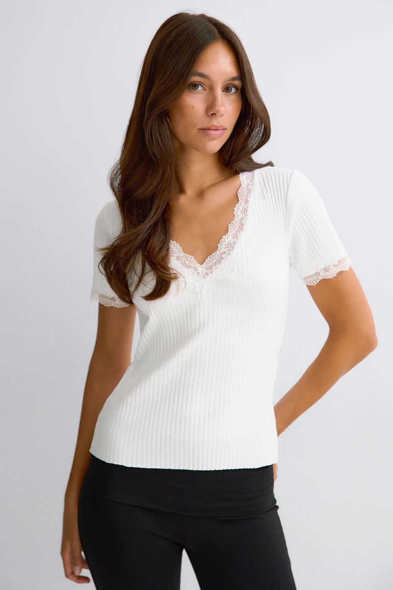 Haut blanc à côtes, orné de dentelle et à manches courtes.