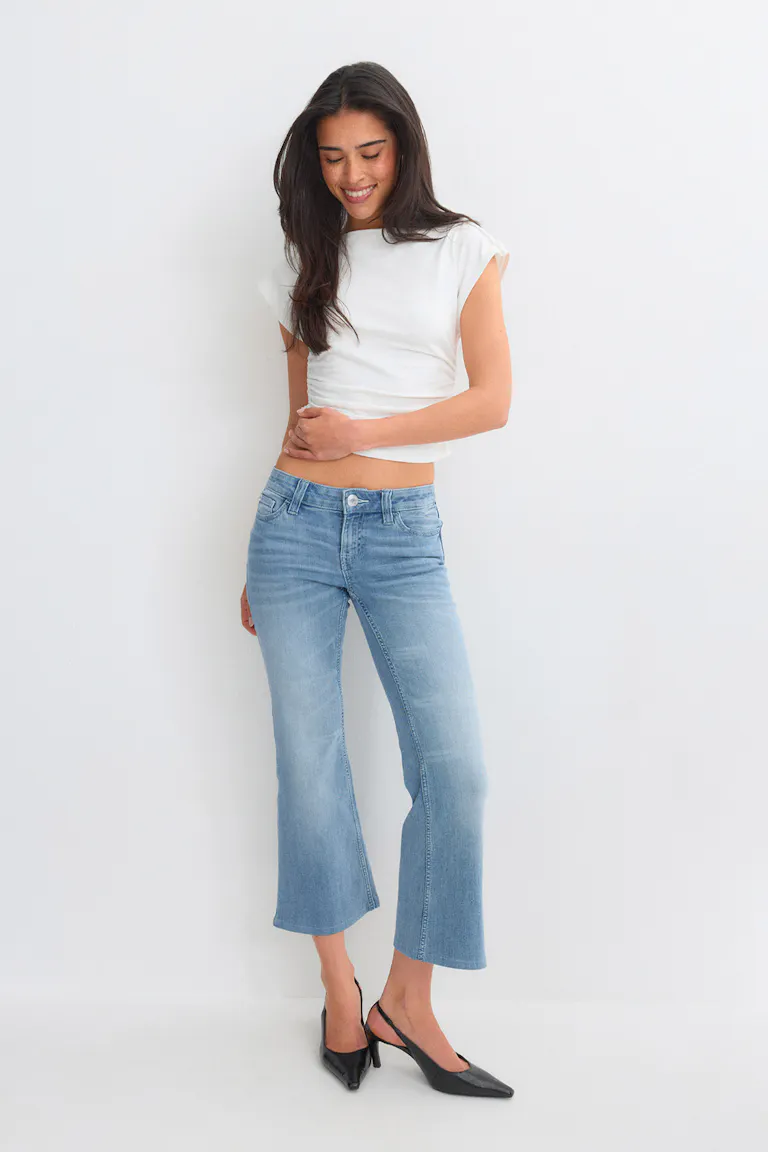 White short-sleeve cropped top with light-blue cropped flared jeans and black pointed-toe slingback heels.