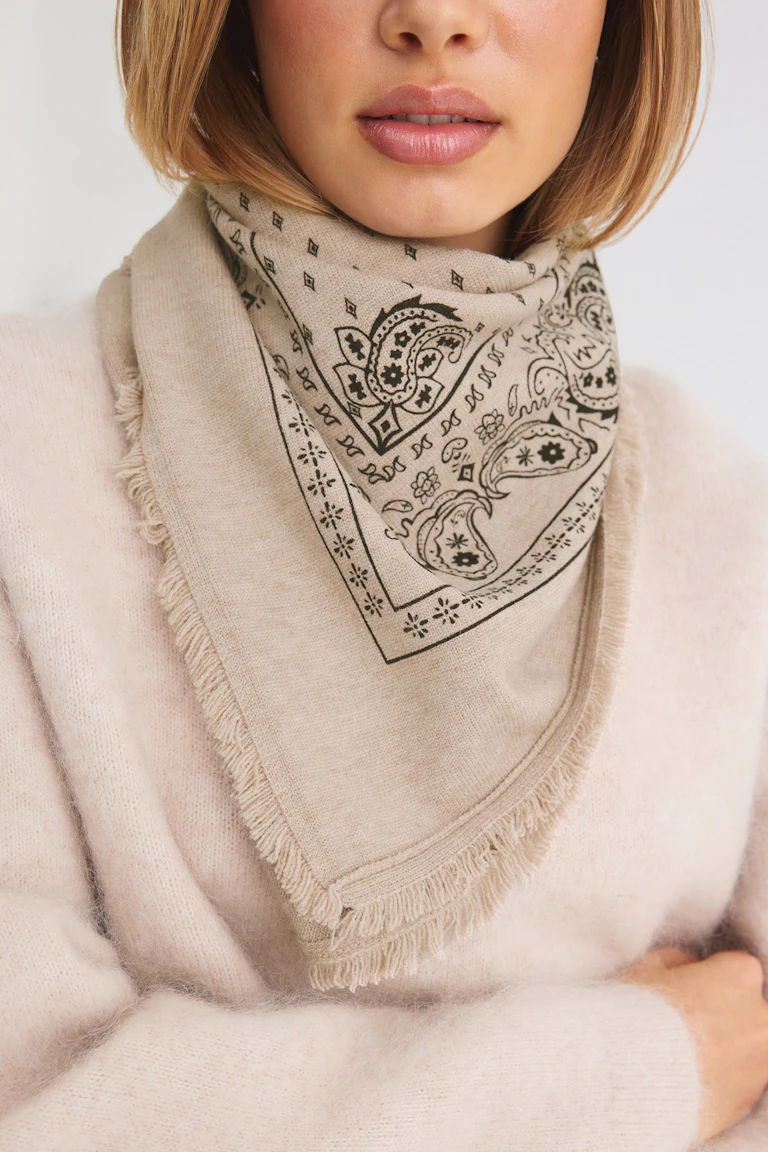 Beige bandana scarf layered over a cream knit sweater.