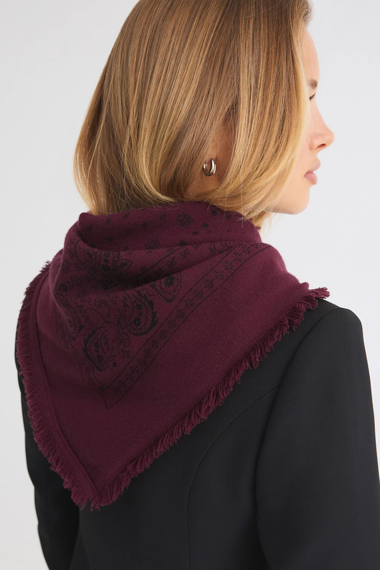 Black blazer with a burgundy patterned fringed scarf.