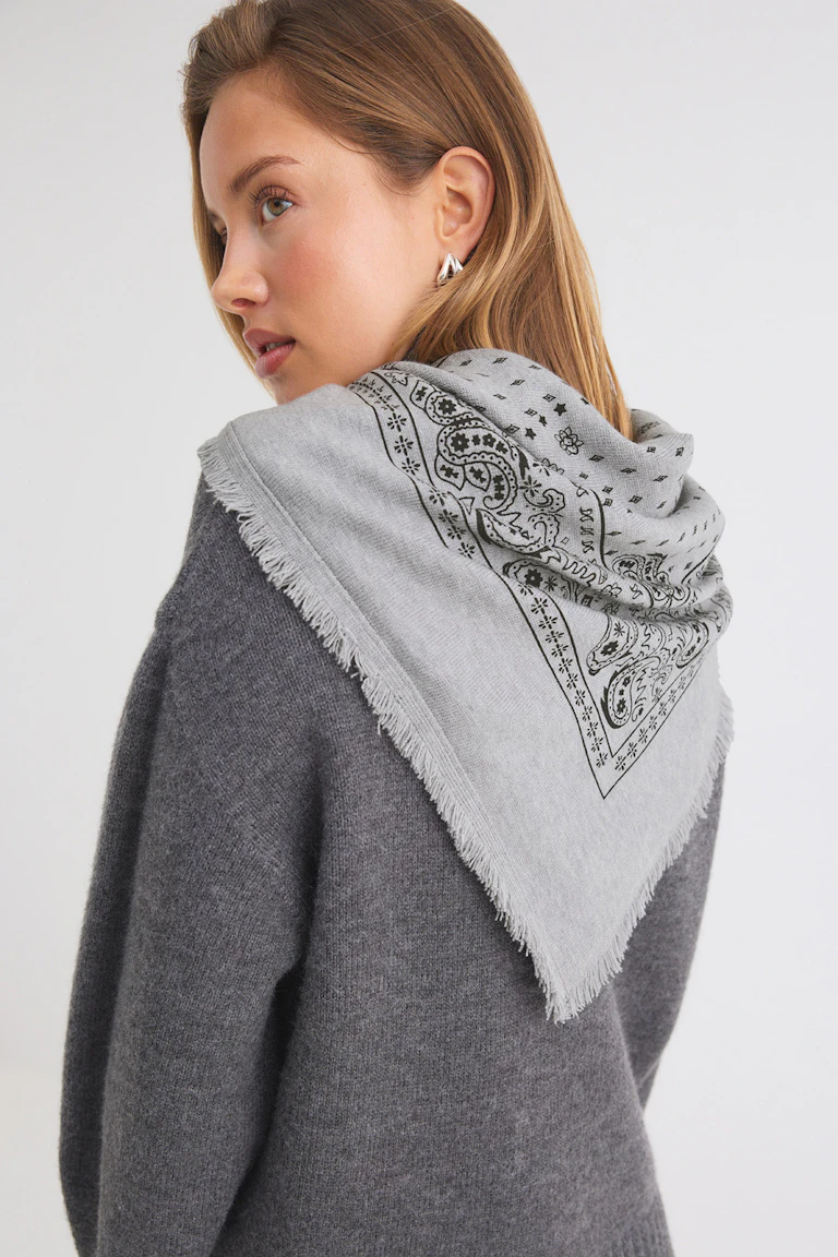 Grey knit sweater with a light grey paisley-print scarf.