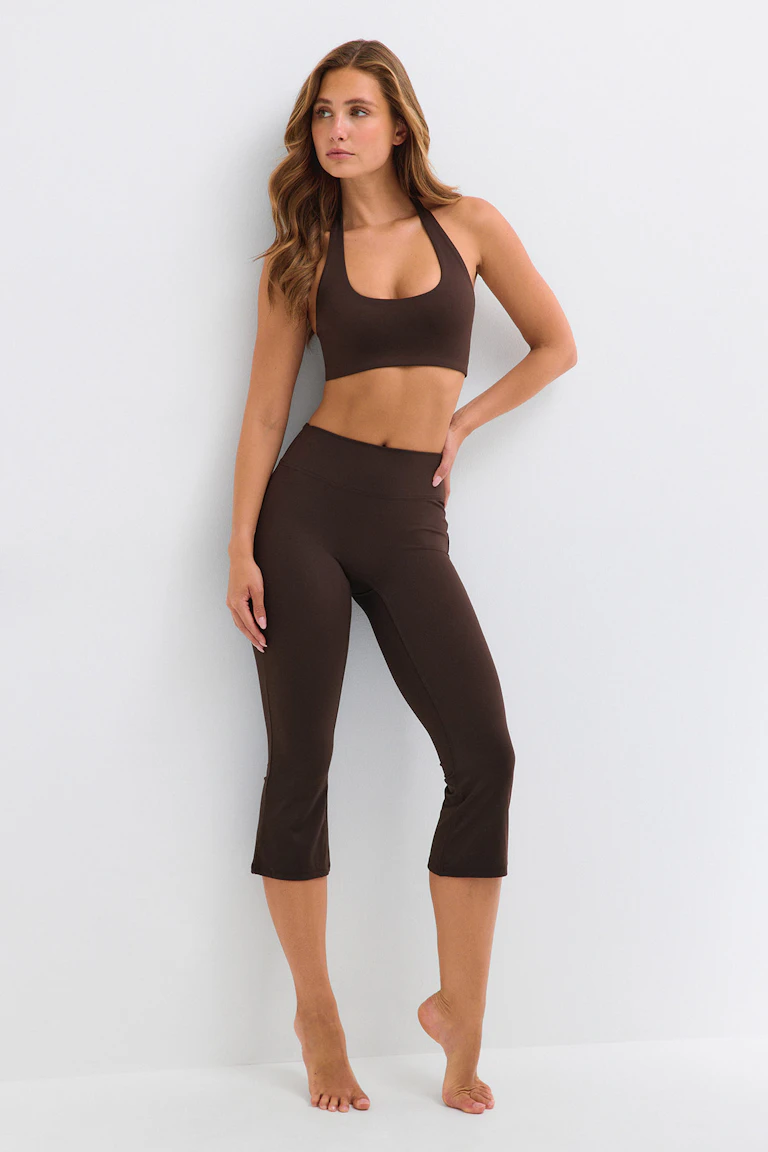 Model in einem dunkelbraunen Neckholder-Sport-BH und dazu passenden kurzen Leggings.