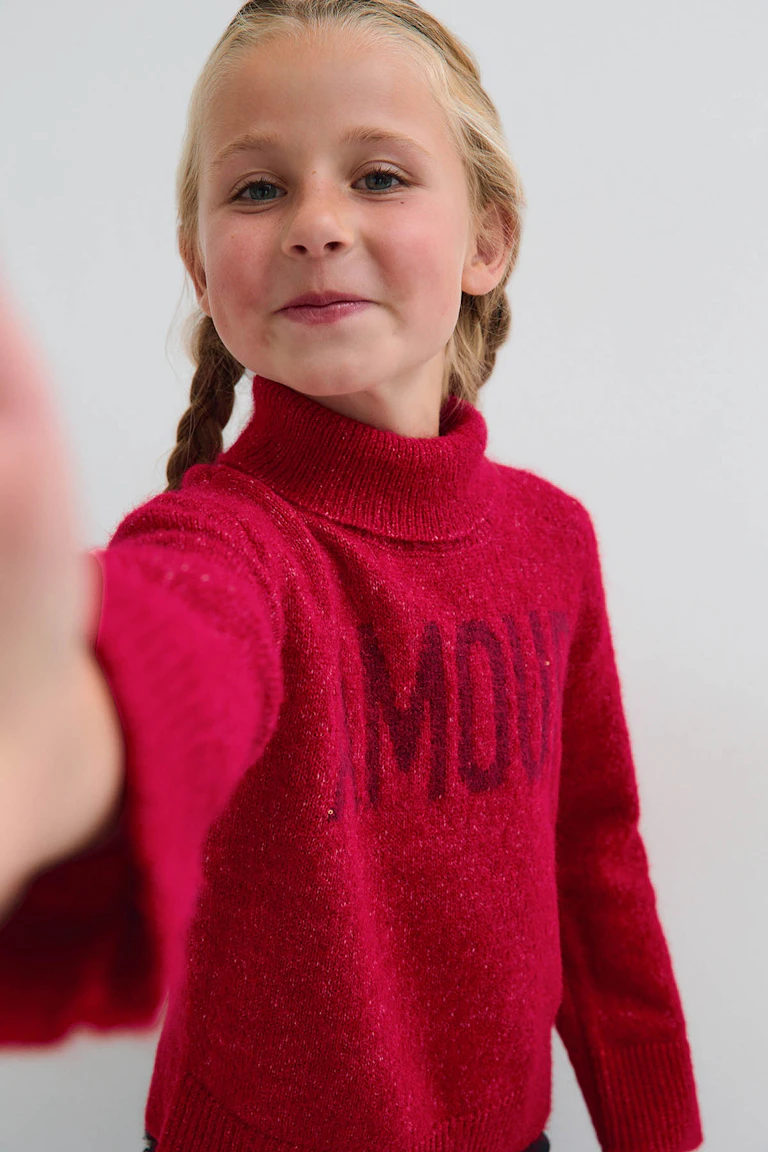Leuchtend pinkfarbener Strickpullover mit Rollkragen.