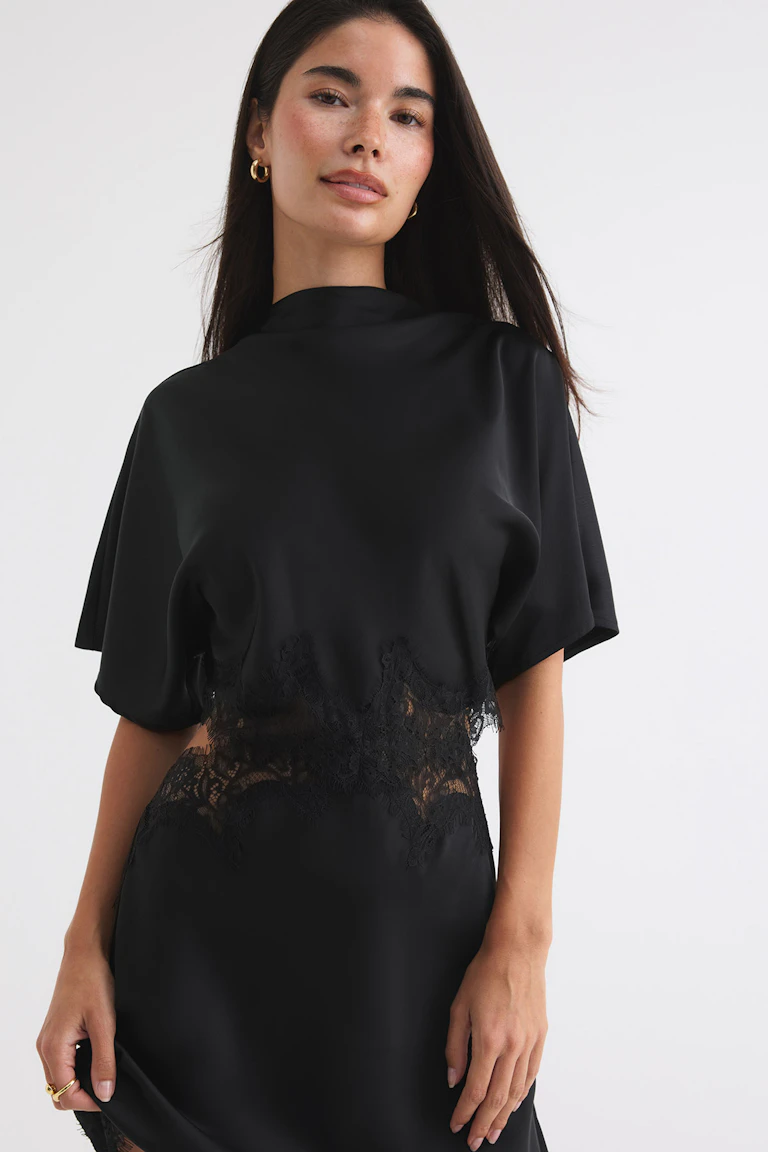 ID 342823, StyleColorSupplier 14423: Svart klänning med korta ärmar och genomskinliga spetsinsatser och spetskanter.