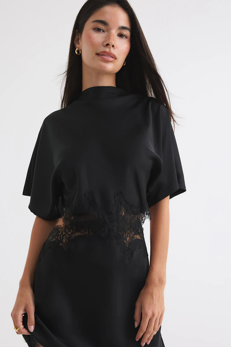 ID 342823, StyleColorSupplier 14423: Musta lyhythihainen mekko, jossa on läpikuultavia pitsiosia ja -reunuksia.