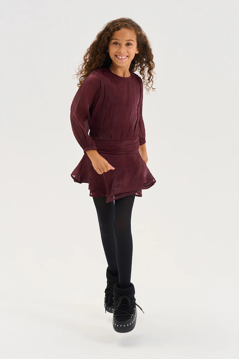 Ein burgunderrotes Langarmkleid mit geraffter Taille, schwarze Strumpfhosen und schwarze Schnürstiefel.