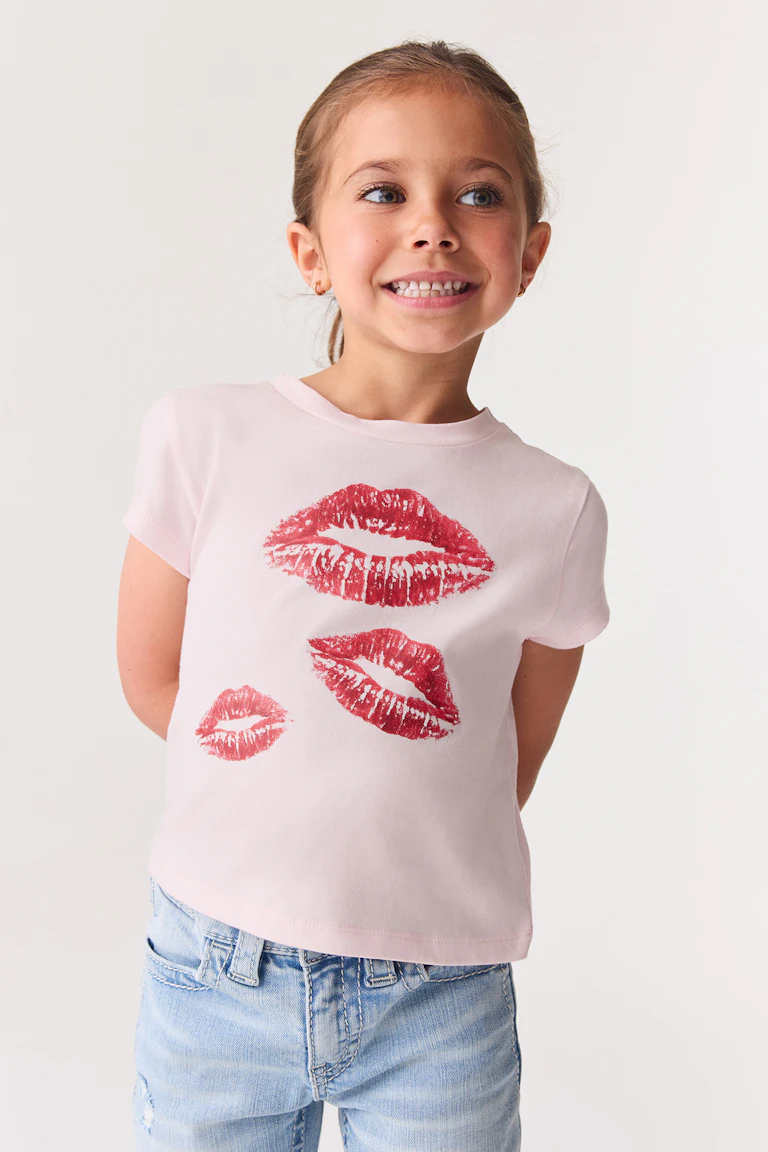 Ein hellrosa T-Shirt mit roten Lippenabdrücken und eine hellblaue Jeans.