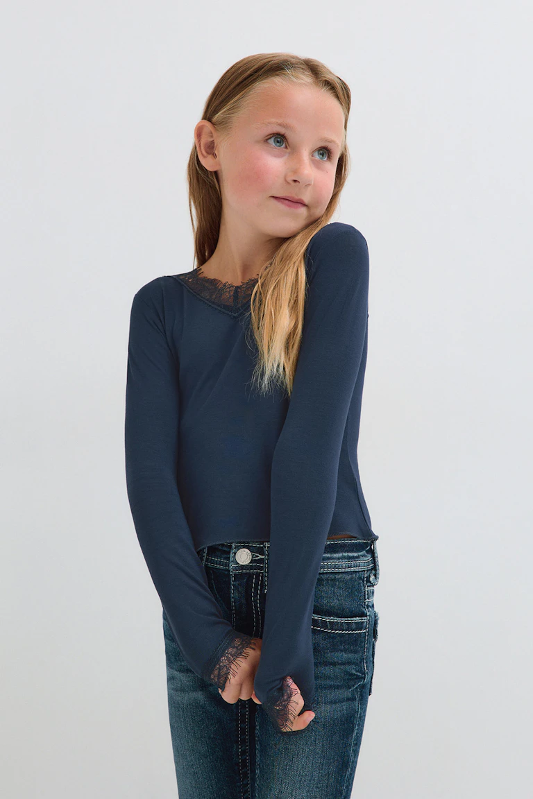 Marineblaues Langarm-Oberteil mit Spitzenbesatz am Ausschnitt und an den Ärmelbündchen, kombiniert mit einer blauen Jeans.