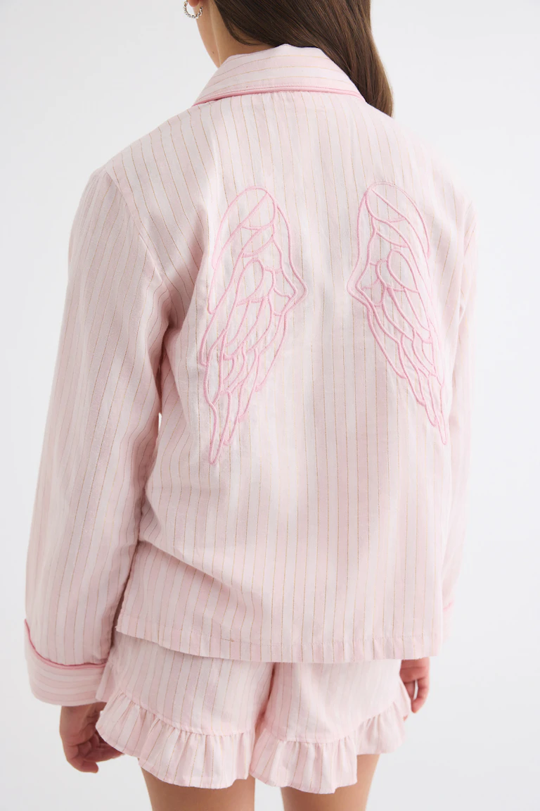 Light pink pinstriped jacket with embroidered wings on the back, paired with matching ruffled shorts.