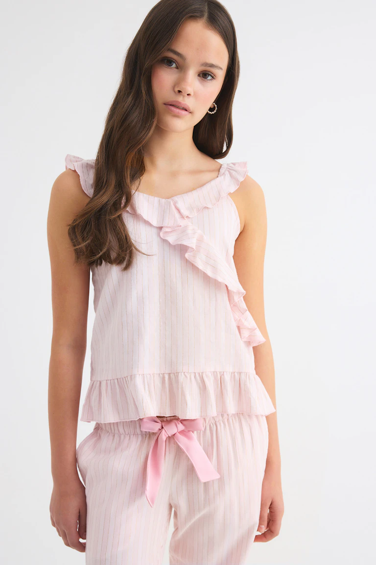 Sleeveless pale pink ruffled top with matching striped trousers and a pink ribbon tie at the waist.