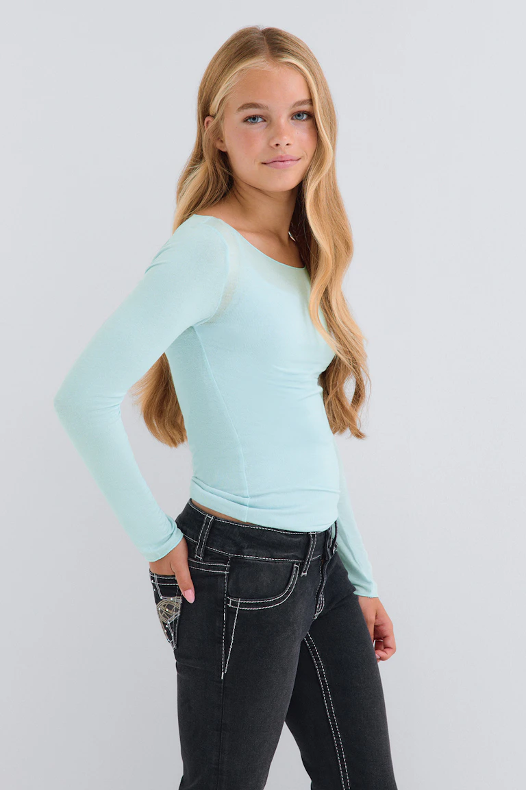 id 344450, StyleColorSupplier 11519-E: De persoon draagt een lichtblauwe, nauwsluitende top met lange mouwen en een zwarte spijkerbroek met contrasterende stiksels.