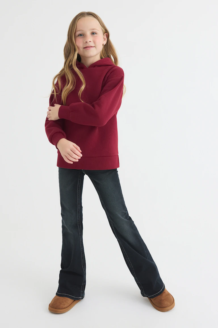 A burgundy hoodie, dark flared jeans, and tan slip-on boots.