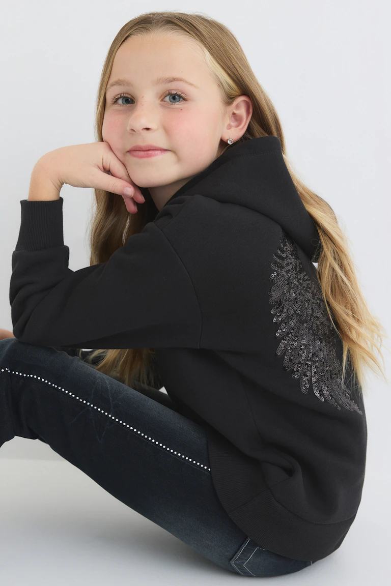 Style 343680, 11519-E: black hooded sweatshirt with sequined wing detail and dark jeans with rhinestone trim.