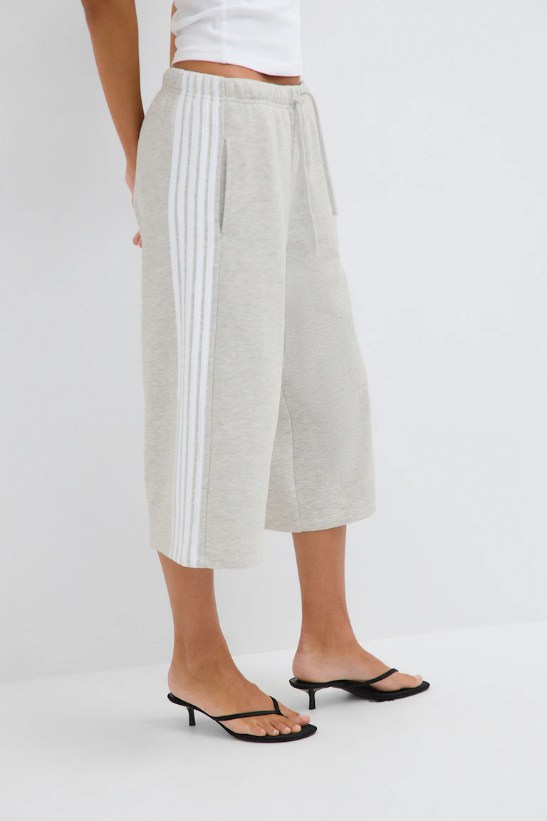 ID 343848, StyleColorSupplier 11519-E: Light grey cropped wide-leg sweatpants with white side stripes, paired with a white cropped top and black heeled thong sandals.