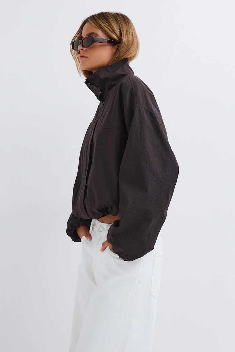 id: 344675, StyleColorSupplier: 19801. Svart jacka med hög krage, vita jeans med vida ben och mörka solglasögon.