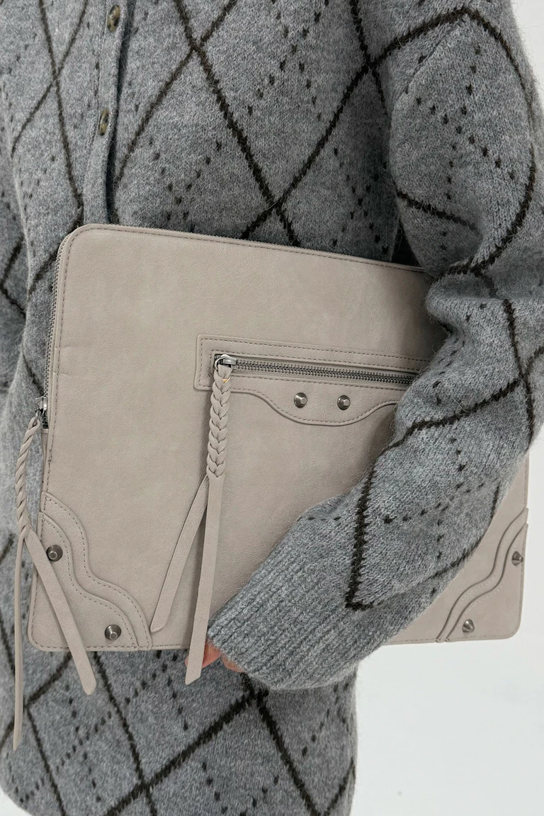En grå strikket cardigan med argylemønster kombineret med en lysbeige læderclutch.