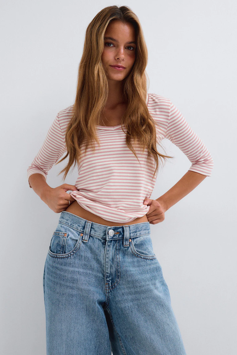 En rosa- och vitrandig topp med trekvartsärmar och ljusblå jeans med vida ben.