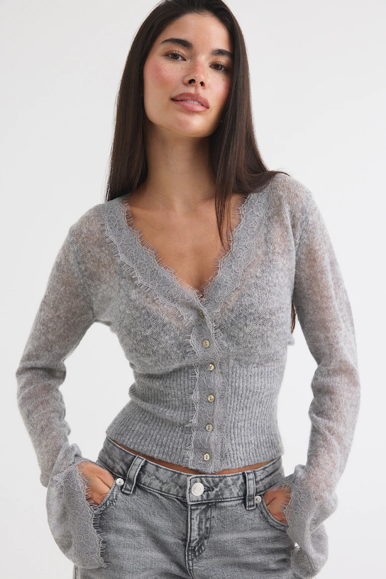 Graue, gerippte Strickjacke mit Spitzenbesatz und Knopfleiste, kombiniert mit einer grauen Jeans.