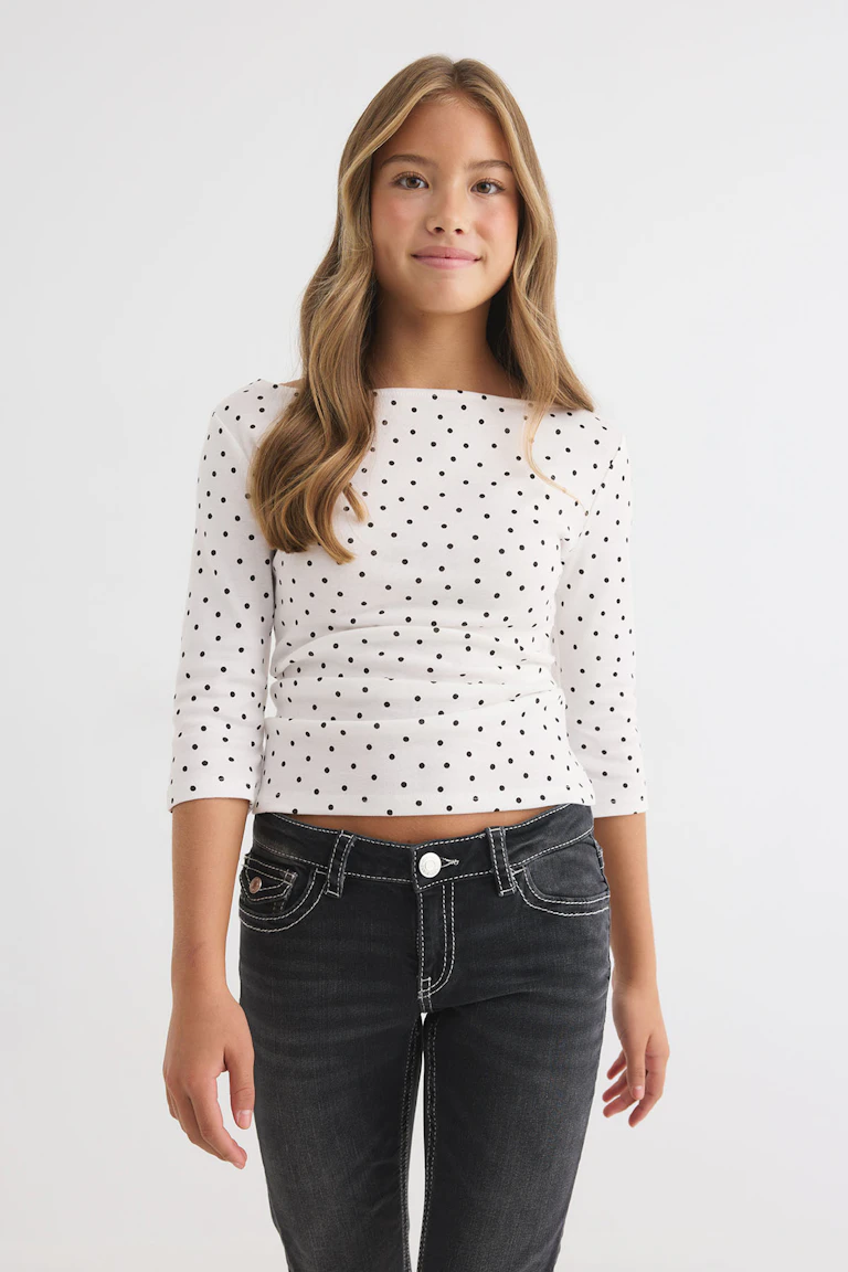 Un haut blanc à manches longues à pois, associé à un jean noir.