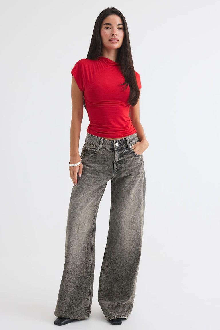 ID 353278, StyleColorSupplier 11519-E: rotes, figurbetontes Kurzarm-Oberteil, graue Jeans mit weitem Bein und schwarze spitze Schuhe.