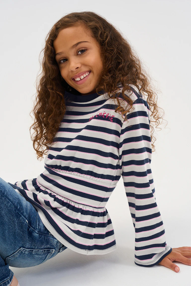 Long-sleeved striped top with pink, navy, and white bands, paired with blue jeans.