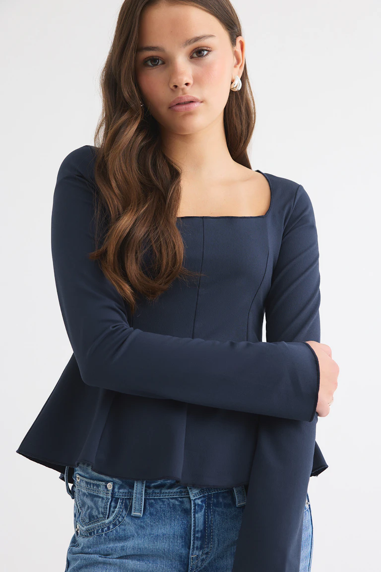 Marineblaues Langarm-Peplum-Oberteil mit quadratischem Ausschnitt, kombiniert mit einer blauen Jeans.