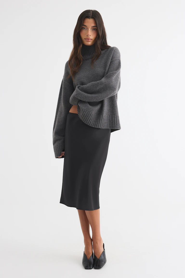 Grey turtleneck sweater with ribbed cuffs and hem, a black midi skirt, and black pointed mules.