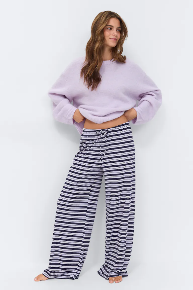 Lavendelfarget genser med oversized rund hals og marineblå og hvite horisontale striper med vide ben og snøring.
